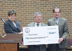 Laminate Technologies announced Monday that it will open a local plant and create 30 jobs. Above, Mary Rae Carter, deputy secretary of commerce and trade for rural economic development, presents a check for $50,000 to Henry County Board of Supervisors Chairman Jim Adams (right) to assist with the LamTech project. Fred Zoeller, co-founder, president and CEO of LamTech, is at center. (Bulletin photos by Mike Wray) 