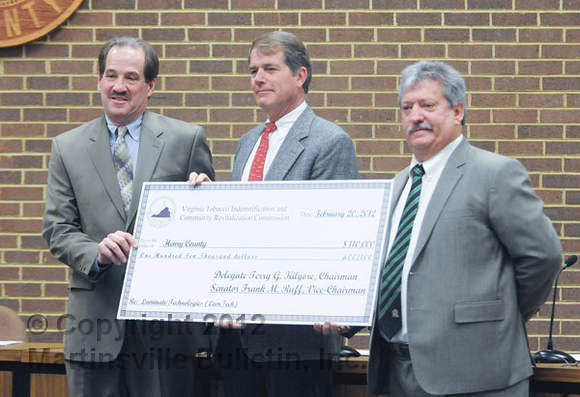 Butch Hamlet (center) of the Virginia Tobacco Indemnification and Community Revitalization Commission presents a check for $110,000 to Henry County Supervisors Chairman Jim Adams (left) to assist with the LamTech project. Fred Zoeller, LamTech president, CEO and co-founder, is at right. (Bulletin photo by Mike Wray) 